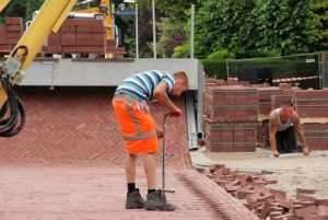 Men laying bricks for a street or sidewalk.